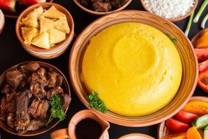 zelfgemaakte Roemeense gerechten met polenta, vlees, kaas en groenten. heerlijke maïspap in kleischotels. mamaliga of polenta, een traditioneel gerecht in de Moldavische, Hongaarse en Oekraïense keuken. foto