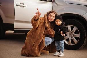 jonge moeder en kind staan in de buurt van hun suv-auto. veiligheid rijden concept.