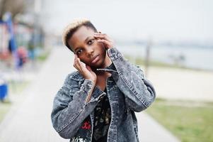jonge duizendjarige Afro-Amerikaanse meisje in de stad. gelukkige zwarte vrouw met draadloze oortelefoons. generatie z-concept. foto