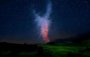 melkweg en roze licht op de bergen. nacht kleurrijk landschap. sterrenhemel met heuvels in de zomer. prachtig universum. ruimte achtergrond met melkweg. reis achtergrond foto