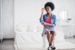 aantrekkelijke Afro-Amerikaanse vrouw met afro haar dragen op rok en jeans jasje, gesteld op witte kamer. modieus zwart model. foto