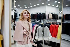 elegantie blond meisje in jas in de winkel van bontjassen en leren jassen.