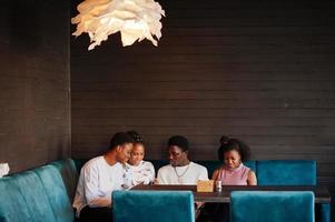 gelukkige Afrikaanse vrienden zitten en chatten in café. groep zwarte volkeren die in restaurant samenkomen. foto