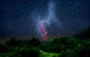 melkweg en roze licht op de bergen. nacht kleurrijk landschap. sterrenhemel met heuvels in de zomer. prachtig universum. ruimte achtergrond met melkweg. reis achtergrond foto