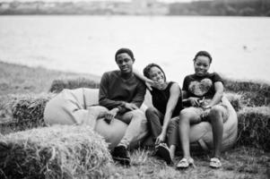 drie Afro-Amerikaanse vrienden chillen en zitten op poefs buiten. foto