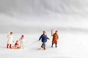 miniatuur mensen gelukkige familie rijden op een slee met sneeuw achtergrond foto