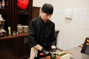 professionele chef-kok draagt in het zwart sushi en broodjes in een restaurantkeuken van japans traditioneel eten. foto