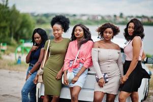 groep van vijf gelukkige Afro-Amerikaanse meisjes poseerden tegen de auto. foto