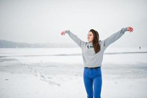 grappige meisjesslijtage op hoody sweater en jeans, bij bevroren meer in de winterdag. foto