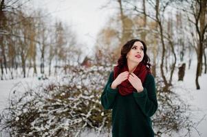 brunette meisje in groene trui en rode sjaal buiten op avond winterdag. foto