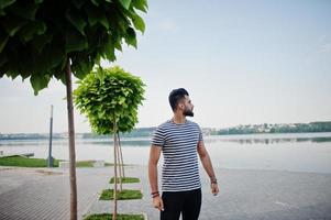 knappe lange Arabische baard man model op gestript shirt buiten geposeerd. modieuze Arabische man. foto