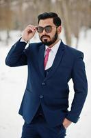 stijlvolle Indiase baard zakenman in pak en zonnebril poseerde op winterdag buiten. foto