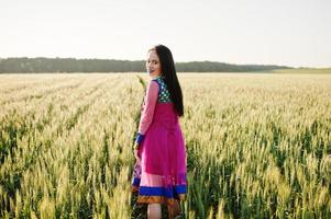 teder indisch meisje in saree, met paarse lippen make-up geposeerd op het veld bij zonsondergang. modieus Indiaas model. foto