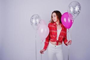 jong meisje in rood geruit overhemd en witte broek met ballonnen tegen een witte achtergrond op studio. foto