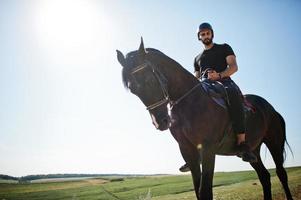 arabische lange baard man draagt zwarte helm, berijdt arabisch paard. foto