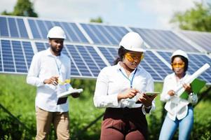 Afro-Amerikaanse technicus controleert het onderhoud van de zonnepanelen. groep van drie zwarte ingenieurs die elkaar ontmoeten op het zonnestation.