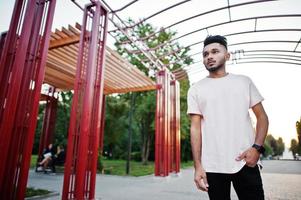 stijlvolle Indiase baard man op roze t-shirt. india model poseerde onder rode boog in het park van de stad. foto