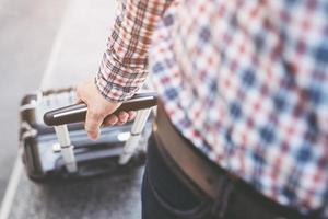 jonge man trekt koffer in luchthaventerminal foto