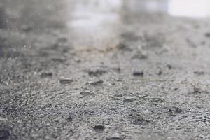 regendruppels in het water zwaar op asfalt schaduw van zwarte schaduw en reflectie van donkere lucht in de stad. hoog contrast in de herfst foto