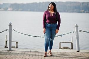 mooie latino xxl model meisje uit ecuador slijtage op violet blouse gesteld tegen meer. foto