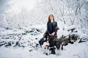 roodharige meisje wandelen in het park met husky hond op winterdag. foto