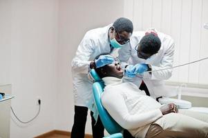 Afro-Amerikaanse man patiënt in tandartsstoel. tandartspraktijk en dokterspraktijkconcept. professionele tandarts die zijn patiënt helpt bij medische tandheelkunde. de tanden van de patiënt boren in de kliniek. foto