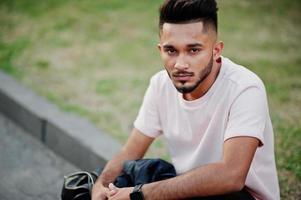 stijlvolle Indiase baard man op roze t-shirt. india model zit aan groene tuin van de stad. foto