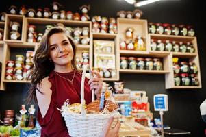 meisje in het rood met verschillende producten op de mand bij deli store. foto