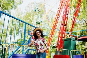 portret van brunette meisje in roze bril en hoed met ijs in pretpark. foto