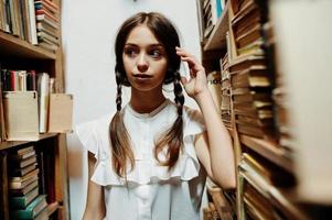 meisje met staartjes in witte blouse bij oude bibliotheek. foto