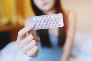 vrouw handen openen anticonceptiepillen in de hand. anticonceptiepil eten. foto