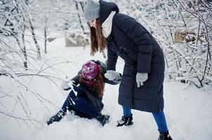 twee grappige meisjes vrienden plezier op besneeuwde winterdag in de buurt van besneeuwde bomen. foto