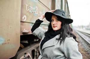 brunette meisje in grijze jas met hoed in treinstation. foto