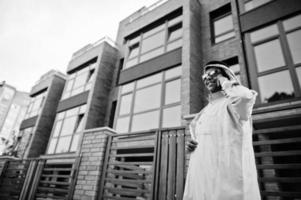 Midden-Oosten Arabische zakenman poseerde op straat tegen modern gebouw met zonnebril, sprekend op mobiele telefoon. foto