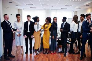 grote groep van elf multiraciale zakenmensen die op kantoor staan. diverse groep medewerkers in formele kleding. foto