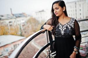vrij indiase meisje in zwarte saree jurk poseerde op balkon. foto