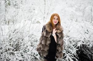 roodharige meisje in bontjas wandelen in besneeuwde winterpark. foto