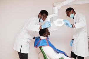 Afro-Amerikaanse mannelijke artsen in professioneel uniform die röntgenfoto's van de patiënt maken. foto