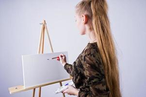 mooie vrouw kunstenaar schilder met borstels en olie canvas poseren in studio geïsoleerd op wit. foto