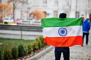 Zuid-Aziatische Indiase mannelijke student met de vlag van india buiten geposeerd. foto