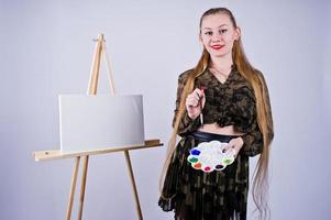 mooie vrouw kunstenaar schilder met borstels en olie canvas poseren in studio geïsoleerd op wit. foto