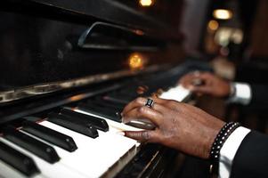 vingers van Afro-Amerikaanse man in zwart pak piano spelen. foto