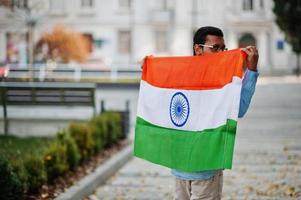 Zuid-Aziatische Indiase mannelijke student met de vlag van india buiten geposeerd. foto