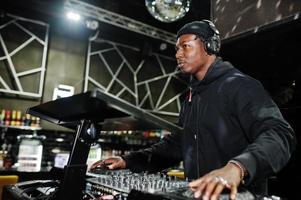 Afro-Amerikaanse dj speelt muziek op dekken in de nachtclub. foto