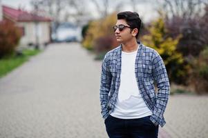 stijlvolle Indiase jongeman met zonnebril draagt casual buiten. foto