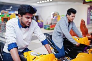 twee aziatische jongens strijden op speed rider arcade game motorrace simulator machine. foto