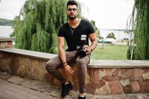 geweldige mooie lange arabische baard macho man fotograaf in glazen en zwart t-shirt met professionele camera bij de hand. foto