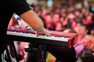 artiest spelen op audio piano op het podium in een concertzaal achter volkeren. foto