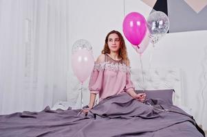 jong meisje met ballonnen op bed gesteld op studio kamer. foto