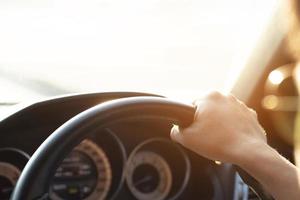 close-up van handen houden stuurwiel jonge man besturen van een auto rijden op de weg. chauffeur reis van reizen. foto